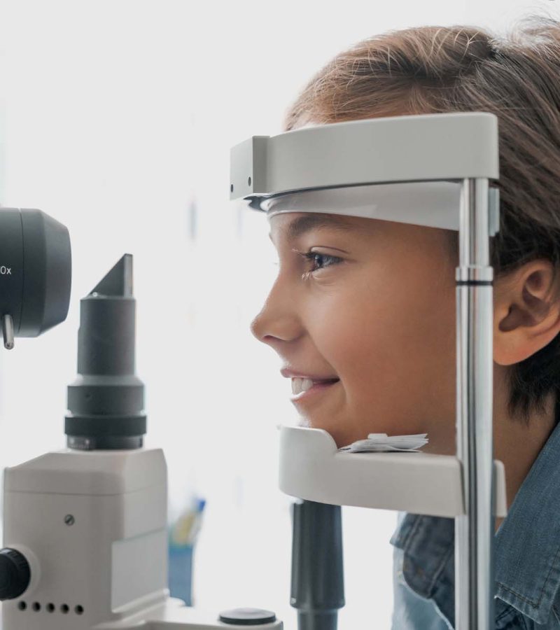 Side view shot of boy checking vision with tonometer at eye clinic